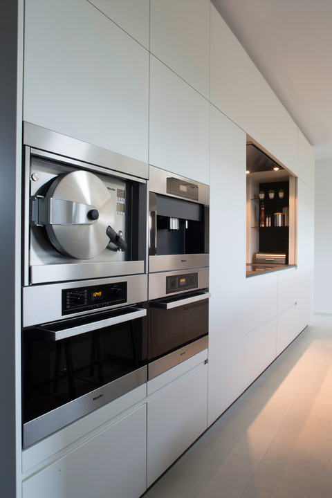 Deze moderne witte design keuken werd door WoonProject op maat gemaakt en ontworpen. De eiland keuken is uitgerust met Miele apparatuur.