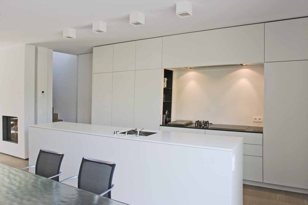 WoonProject verzorgde de totaalinrichting van het interieur van Waterkant in Veurne. Op de foto ziet u een deel van de design witte keuken en woonkamer.