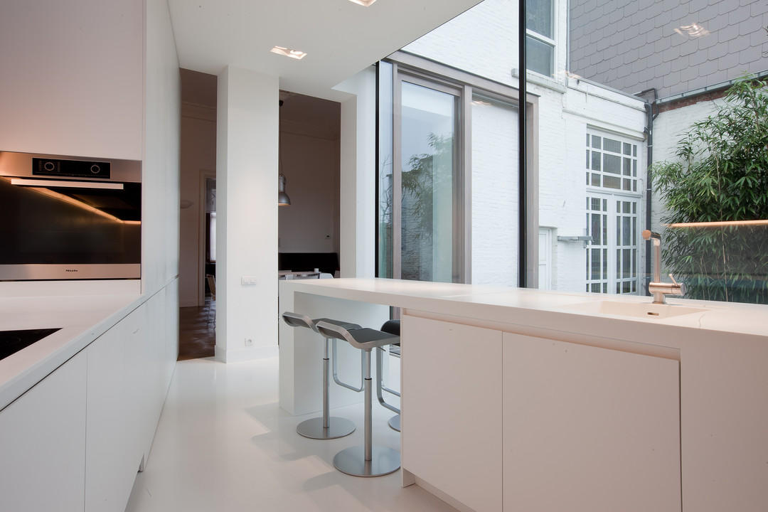 Deze moderne keuken is afgewerkt met wit laminaat met Corian (kunststof) werkblad zonder naad. Gemaakt en geplaatst door WoonProject in Aalter.
