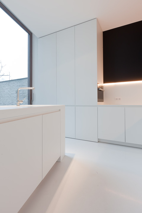 Mooie design keuken ontworpen door WoonProject in Aalter. De keuken bestaat uit wit laminaat met Corian (kunststof) werkblad zonder naad.