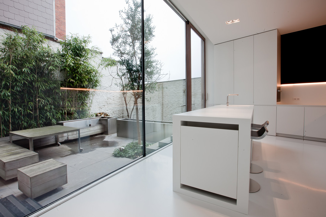 Deze mooie witte design keuken gemaakt door WoonProject heeft uitzicht op het terras.